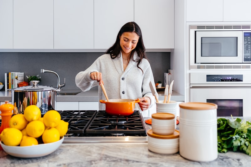 Modern pastel ceramic skillet and wooden spoons on a sunny kitchen prep island