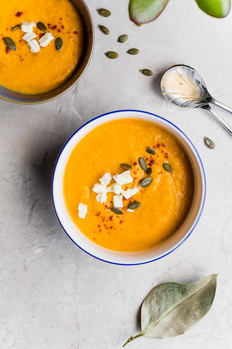 Creamy golden butternut squash soup in ceramic bowl with cream swirl and roasted pumpkin seeds